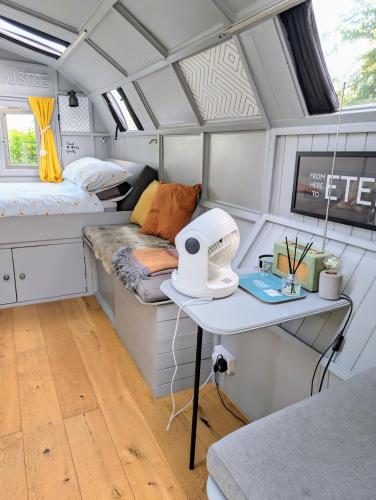 a tiny house with a bed and a desk in it at Wilderness Wagon Bow Top Gypsy Wagon in Lindfield