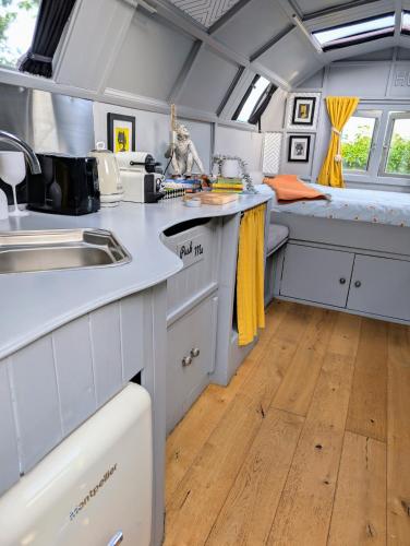a kitchen with white cabinets and a sink and a bed at Wilderness Wagon Bow Top Gypsy Wagon in Lindfield