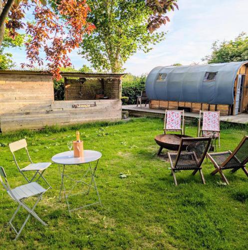 a group of chairs and a table in the grass at Wilderness Wagon Bow Top Gypsy Wagon in Lindfield