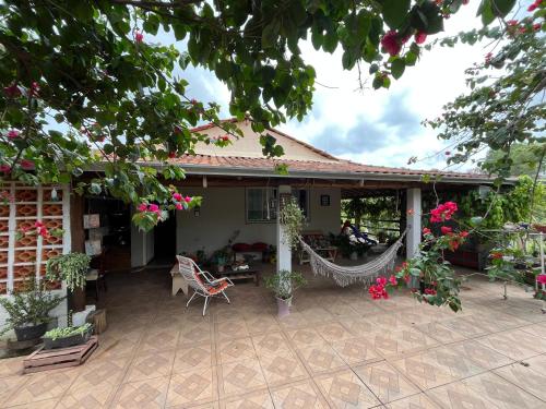una casa con un patio con hamaca y flores en Casa Paz & Sossego a 14minutos do centro, en Poços de Caldas