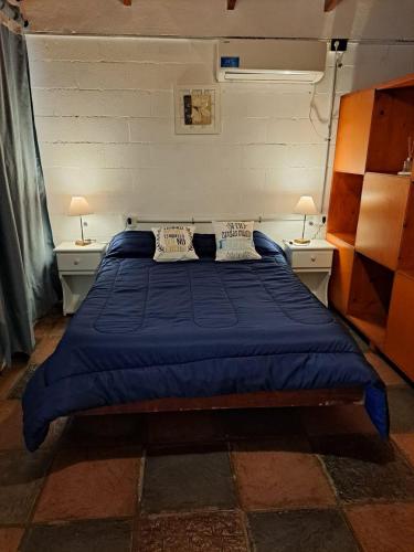 a bedroom with a blue bed with two tables and two lamps at ALOJAMIENTO SERRANO BIS in Villa Giardino