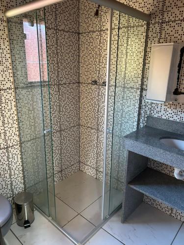 a glass shower in a bathroom with a sink at Alta Colina Chalés in Nova Friburgo