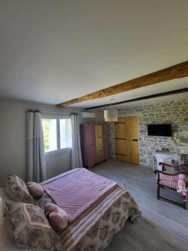 une chambre avec un grand lit et un mur en pierre dans l'établissement Domaine de LOLI, à Saint-Girons