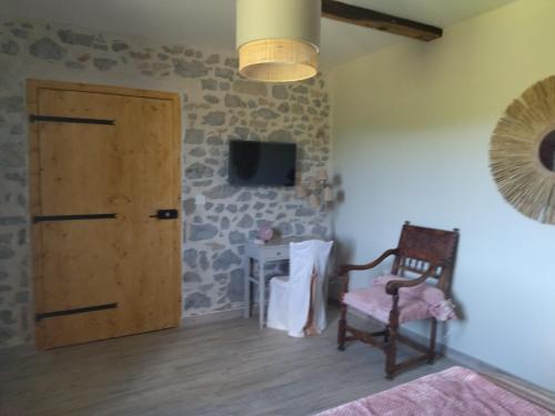 Zimmer mit einer Tür, einem Stuhl und einem TV in der Unterkunft Domaine de LOLI in Saint-Girons