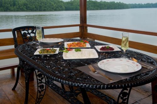 une table avec des assiettes de nourriture sur un bateau dans l'établissement Okvin River Villa, à Bentota