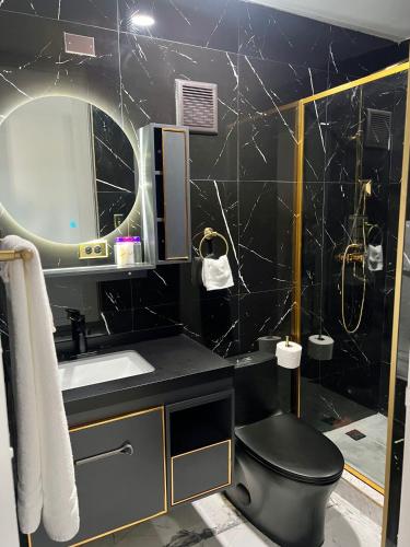 a black bathroom with a toilet and a sink at 1912 Boutique Hotel in Cayey