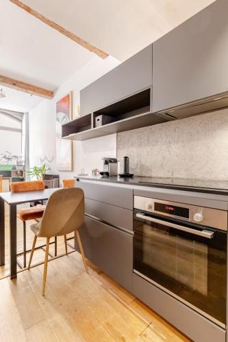 une cuisine avec des appareils en acier inoxydable et une table dans l'établissement Logement de charme aux Carmes, à Toulouse