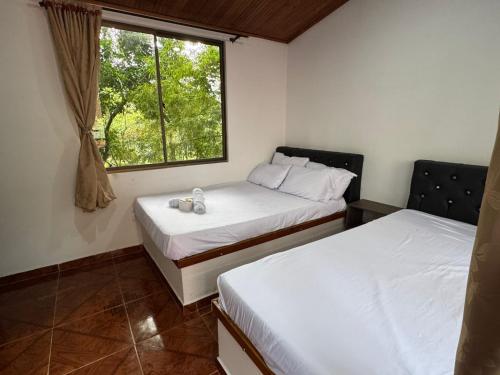 two beds in a room with a window at Hotel la Isabella SM in Villeta