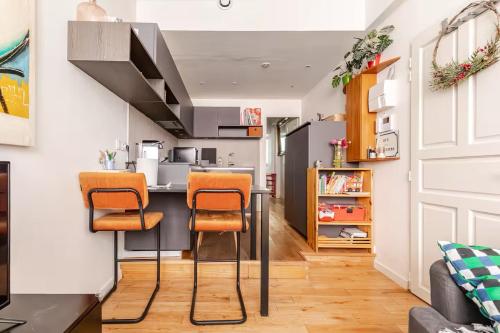 une cuisine ouverte avec des chaises orange et un comptoir dans l'établissement Logement de charme aux Carmes, à Toulouse