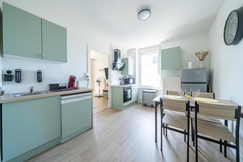 une cuisine avec des placards bleus et une table avec des chaises dans l'établissement Le Julie -Spacieux - 5 pers' - 3 beds - Gare 500m, à Homécourt