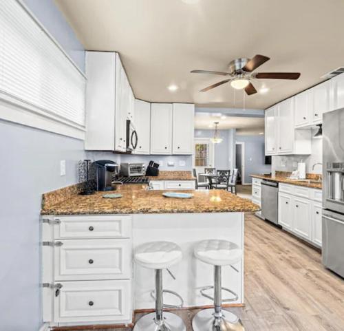 una cocina con armarios blancos y una isla con taburetes. en Galveston Waterfront, en Galveston