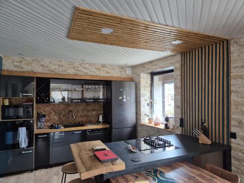une cuisine avec un comptoir noir et une table dans l'établissement Cosy Maison Familiales, à La Llagonne