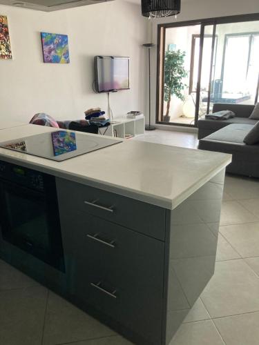 une cuisine avec un comptoir blanc dans le salon dans l'établissement Superbe 2 pièces 55 m2 Juàn les pins, à Juan-les-Pins