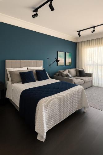 a bedroom with a large bed and a couch at Studio Campo Belo com Rooftpo Piscina e Metrô in Sao Paulo