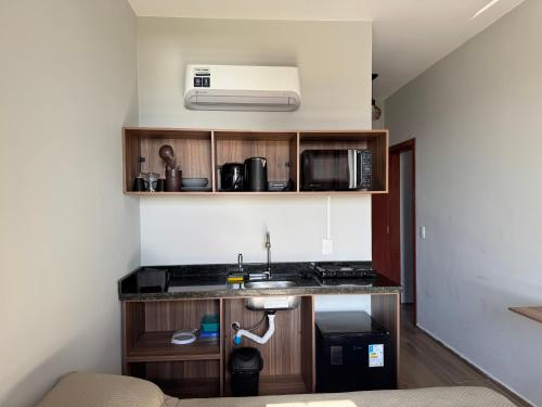 une cuisine avec un évier et un micro-ondes dans l'établissement Apartamento de Frente para Lagoa - Ap 103, à Laguna