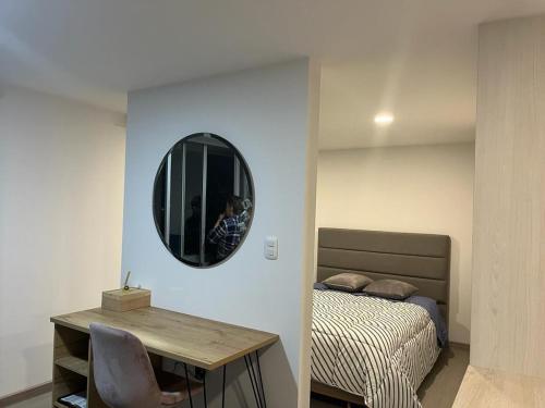 a bedroom with a bed and a table and a mirror at PAIPA Hermoso apartamento en RUSTICO 709 in Paipa