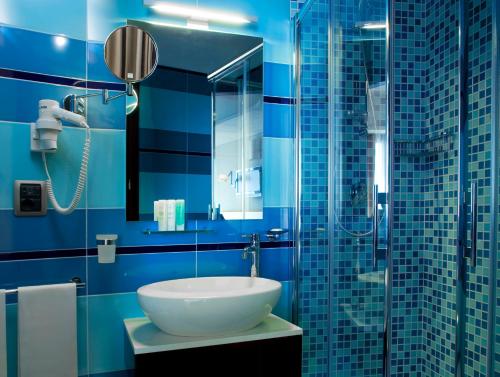 a blue bathroom with a sink and a shower at Taormina Panoramic Hotel in Taormina