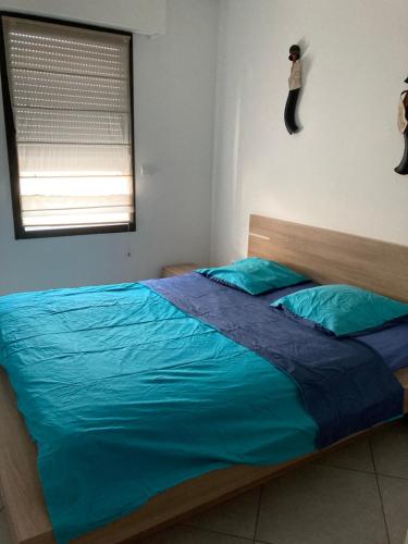 une chambre avec un lit avec des draps bleus et une fenêtre dans l'établissement 2 pièces 55 m2 Juàn les pins, à Juan-les-Pins