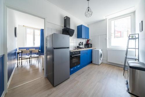 La cuisine est équipée de placards bleus et d'un réfrigérateur en acier inoxydable. dans l'établissement Bleu Océane - Wifi - Gare - 3 lits - Tout équipé, à Homécourt
