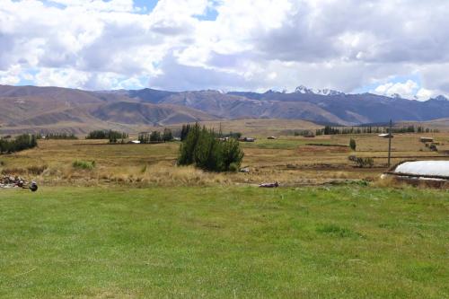 a field of green grass with mountains in the background at Casa Cóndor Ausangate in Tinke