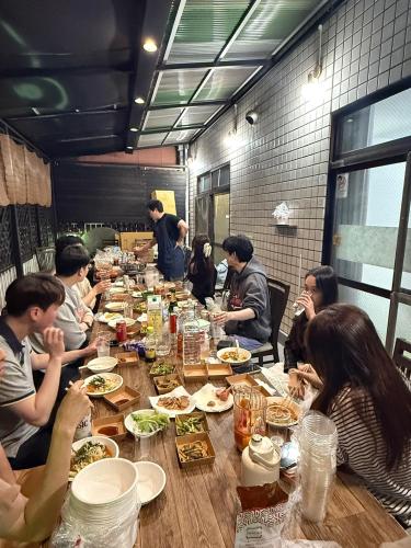 a group of people sitting at a long table eating food at NAMBA Dotonbori HoYaHouse2 in Osaka