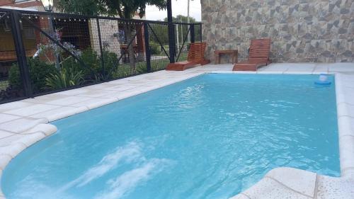 a large blue swimming pool with two chairs and a table at Cabañas bajos medanales in Victorica