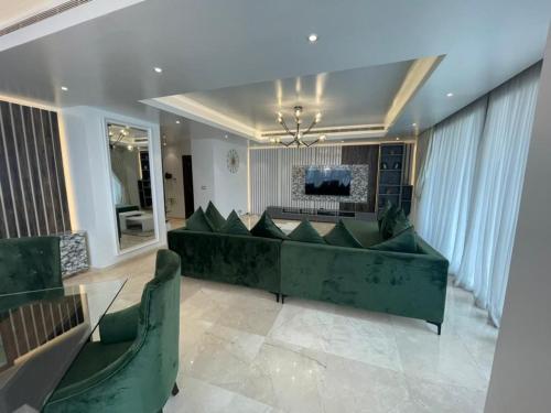 a living room with a green couch and a television at Eko Atlantic Units Of 2Bedrooms & 3Bedrooms Apartments, Lagos in Inupa