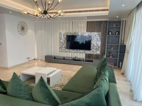 a living room with a green couch and a tv at Eko Atlantic Units Of 2Bedrooms & 3Bedrooms Apartments, Lagos in Inupa