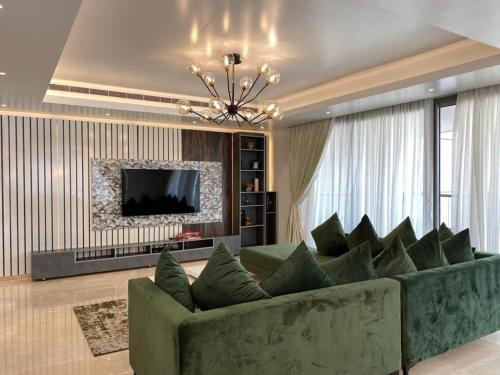 a living room with a green couch and a television at Eko Atlantic Units Of 2Bedrooms & 3Bedrooms Apartments, Lagos in Inupa