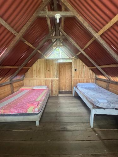 two beds in a wooden room with a ceiling at SURF HOUSE ESTILO LIBRE in Buenaventura