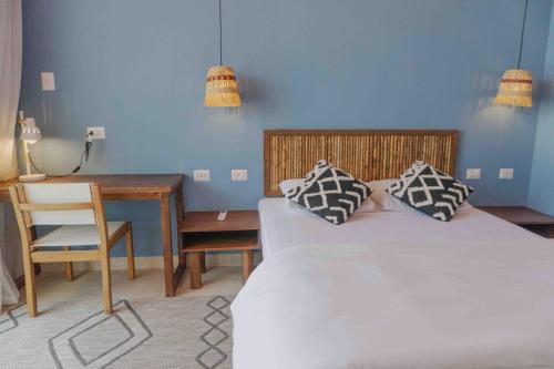 a bedroom with a bed and a desk and a chair at qema Mancora in Máncora