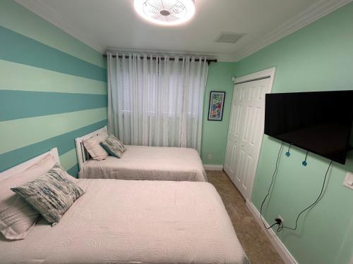 een slaapkamer met twee bedden en een flatscreen-tv bij Blue Orchid Palms in Nassau