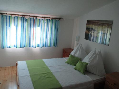a bedroom with a bed with green and white pillows at Guest House Villa Daniel - Two Bedroom Apartment with Balcony in Omiš