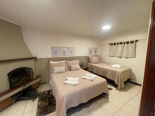 a room with two beds and a fireplace and a tv at Pousada Flor de Lua Monte Verde in Monte Verde