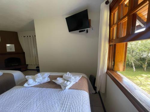 a room with a bed and a window with towels at Pousada Flor de Lua Monte Verde in Monte Verde