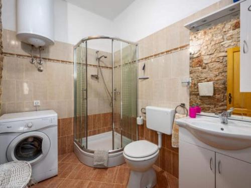 a bathroom with a toilet and a sink and a washing machine at Holiday Home Luna - Holiday Home in Mednjan