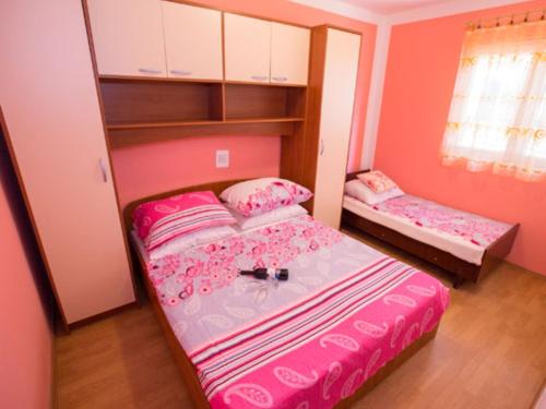 a small bedroom with two beds in a room with pink walls at Apartments Zora - Standard One Bedroom Apartment with Balcony A1 in Lopar