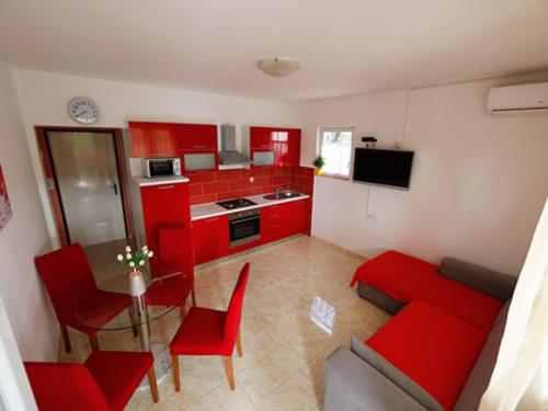 a kitchen with red cabinets and a red couch and a table at Apartments Zora - Standard One Bedroom Apartment with Balcony A1 in Lopar