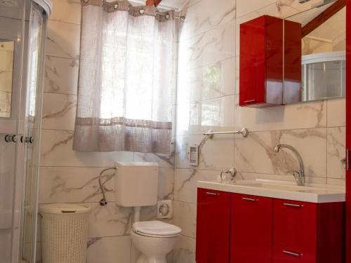 bagno con servizi igienici, lavandino e armadi rossi. di Authentic Dalmatian Treasure Homes - House Stone a Orebić (Sabbioncello)