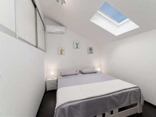 a white bedroom with a bed and a skylight at Holiday Home Lea - Three Bedroom Holiday Home with Terrace and Sea View in Maslinica