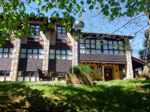 a house on a hill with a green lawn at Hotel El Carmen in Ribadesella