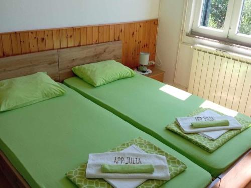 two beds in a room with green sheets and towels at Apartments Julia - Triple Room Julia 4 in Martinšćica