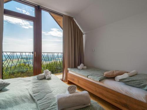 two beds in a room with a large window at Villa Breg - Four Bedroom Villa with Pool, Hot-Tub and Sauna in Kamešnica