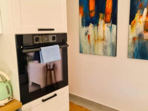 a microwave in a kitchen with two paintings on the wall at Apartment Torre Senj - Two Bedroom Apartment with Balcony and Mountain View in Senj