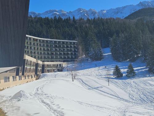 a large building in the snow with mountains in the background at Studio cabine 4 pers Cosy esprit chalet Les glovettes in Villard-de-Lans