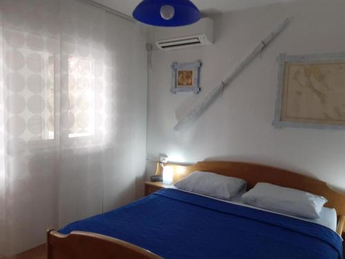 une chambre avec un lit bleu et une fenêtre dans l'établissement Guest House Green Corner Supetarska Draga - Studio Apartment with Terrace And Sea View, à Rab