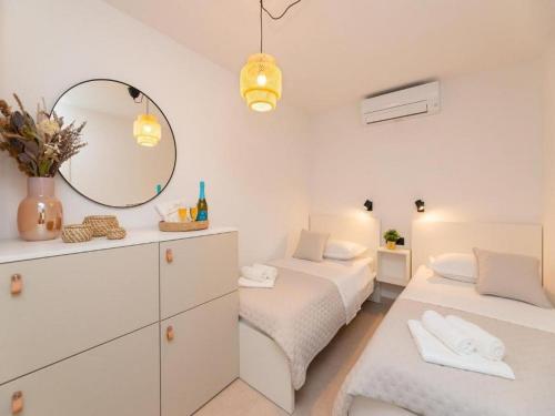 ein weißes Schlafzimmer mit zwei Betten und einem Spiegel in der Unterkunft Villa ADRIANA - Two bedroom Villa with swimming pool in Nerežišće