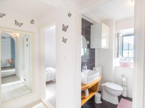 a white bathroom with a toilet and a sink at Four Bedroom Holiday Home with Sea View in Ston