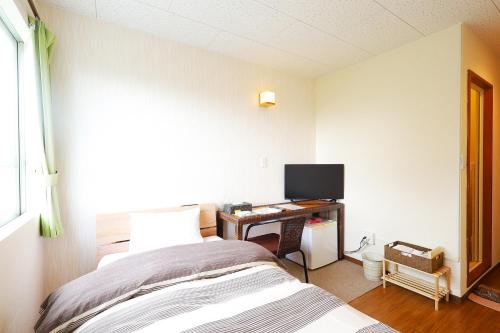 a bedroom with a bed and a desk with a computer at 民宿さざんか in Okinawa City