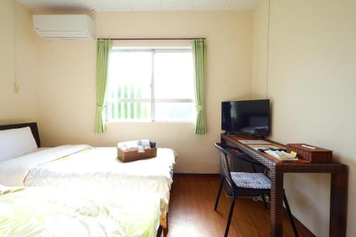 a room with a desk with a computer and a bed at 民宿さざんか in Okinawa City